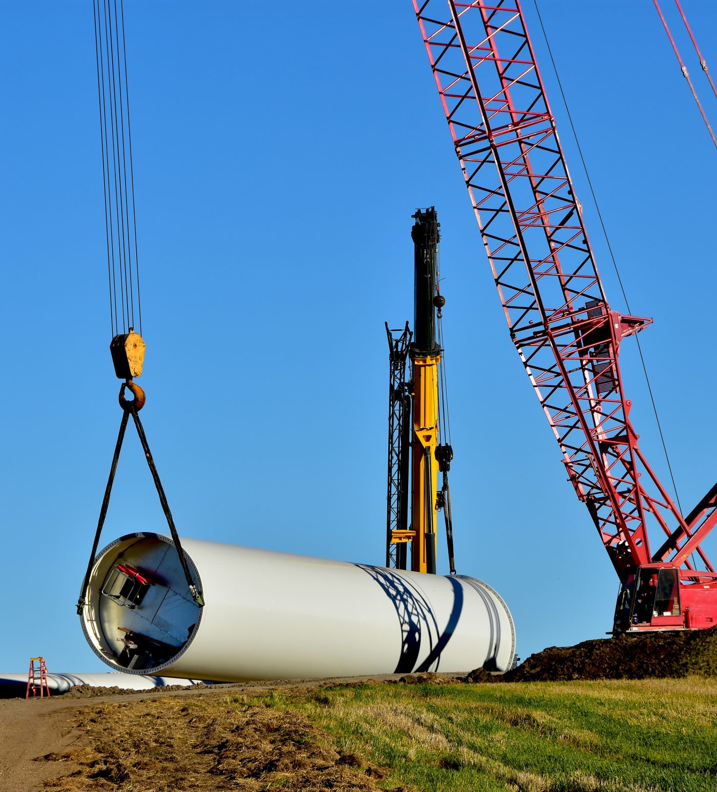 construction equipment installing base section of tower for wind turbine.